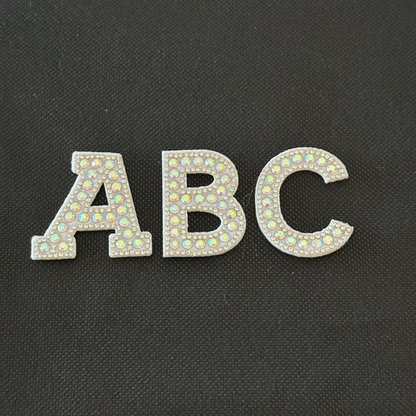 Silver 'ABC' letters with rhinestone embellishments on a black background