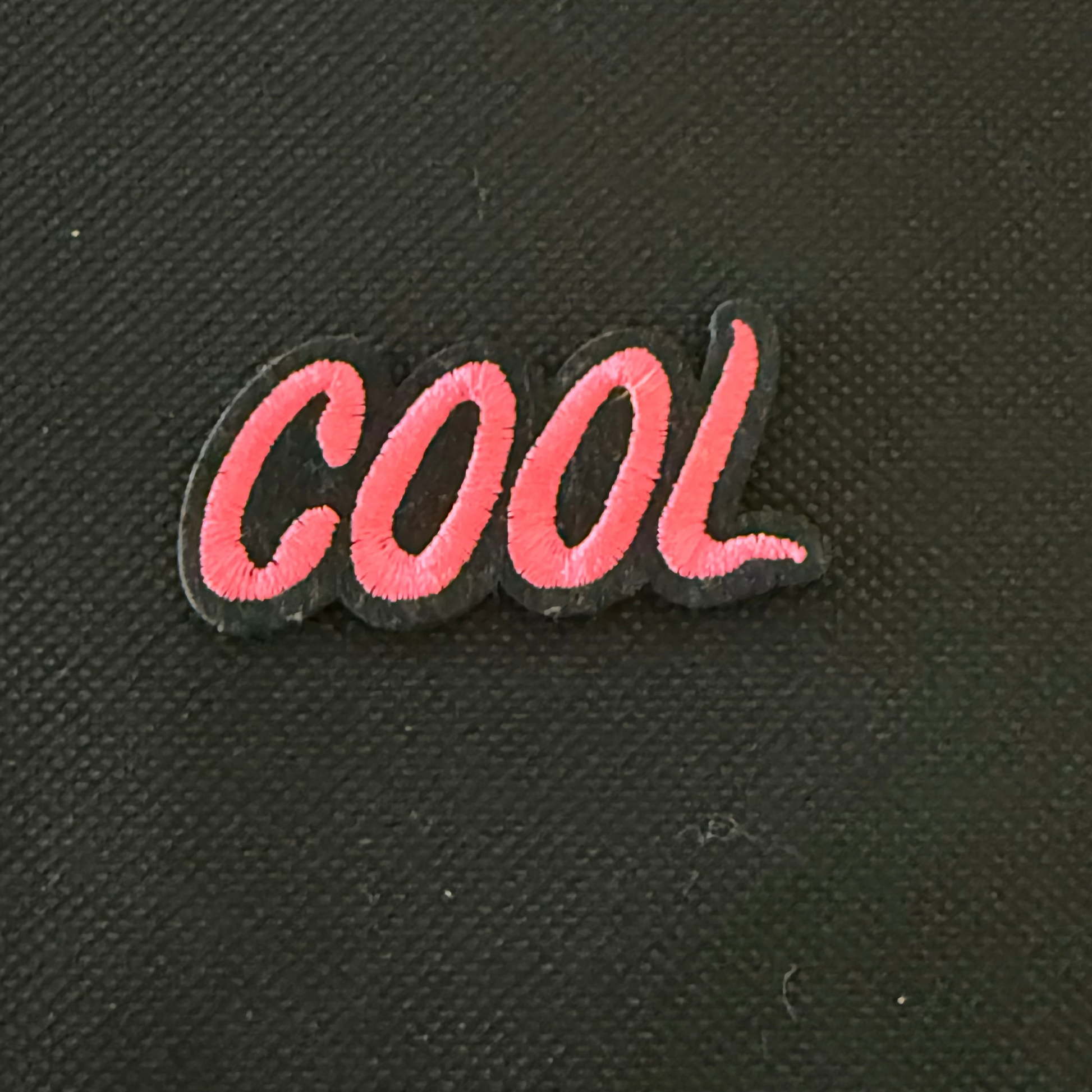 Pink 'COOL' patch on a black textured background