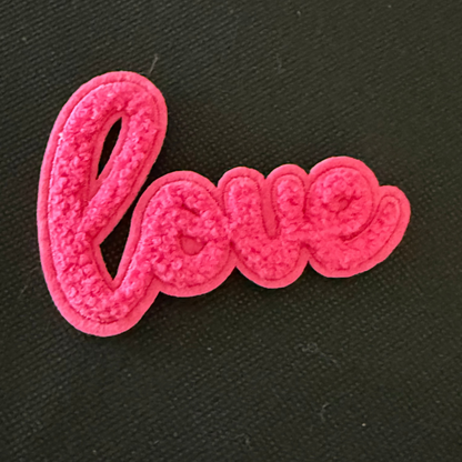 Pink 'love' patch on a black background