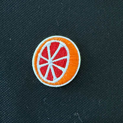 Circular patch with orange and red design on a dark fabric background