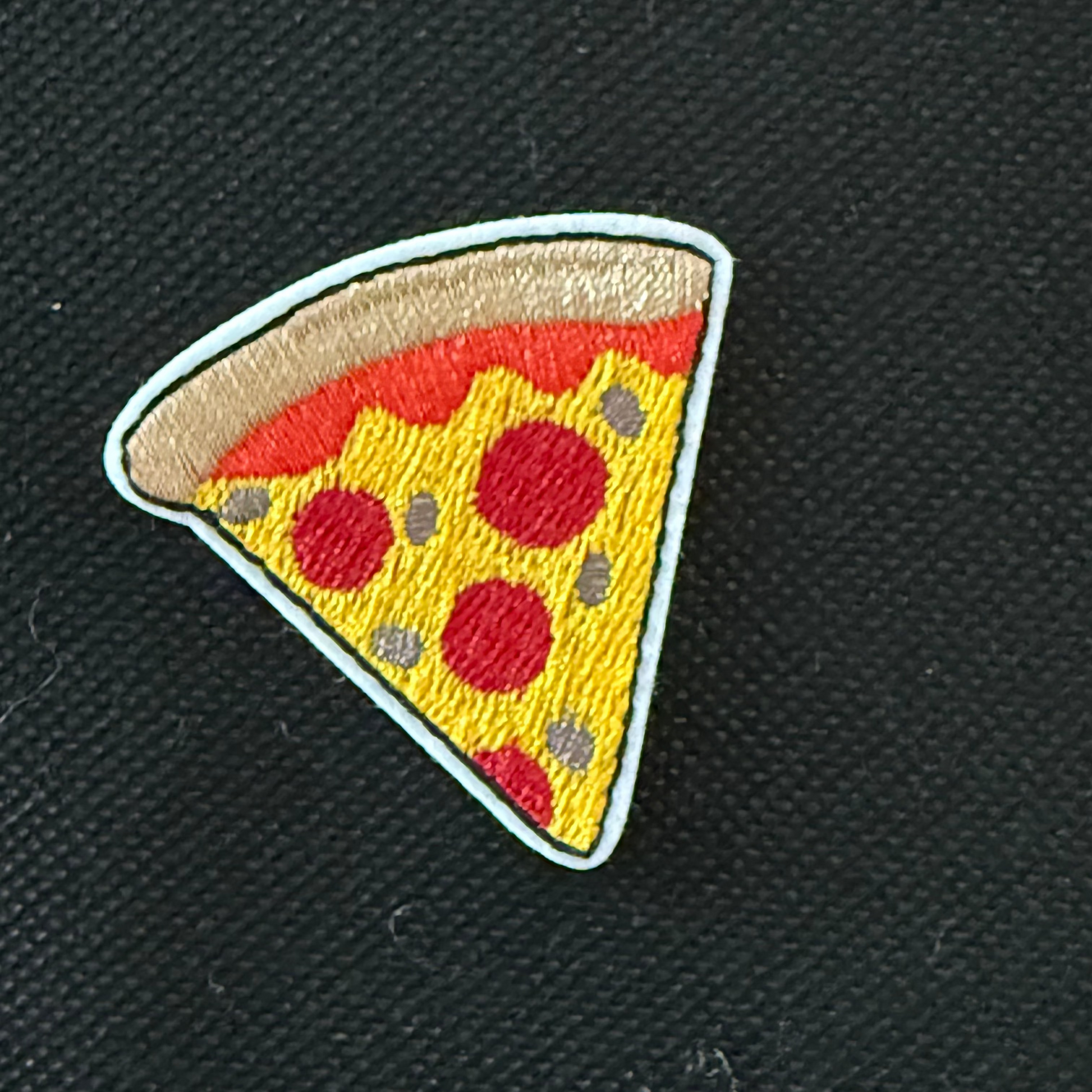 Embroidered patch of a pizza slice on a black background