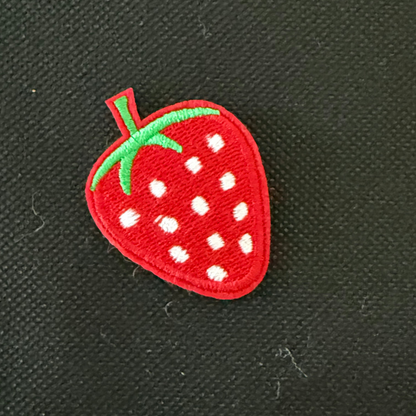 Red strawberry patch with white spots and green stem on a black background