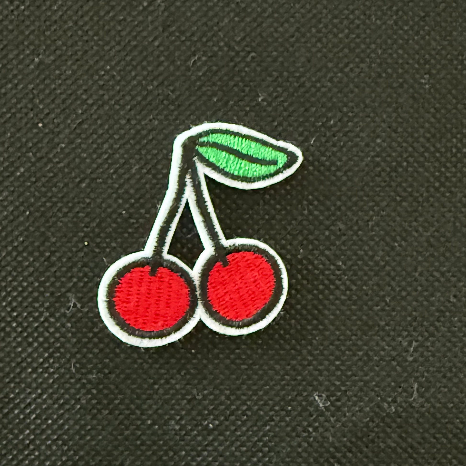 Embroidered cherry design on a black fabric background