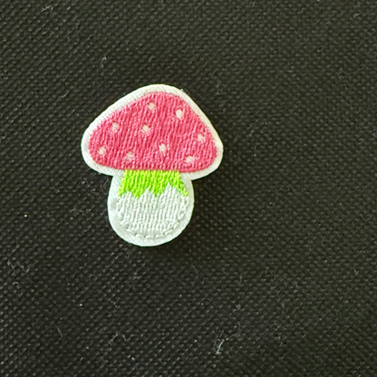 Mushroom-shaped patch with pink cap and green stem on a black background