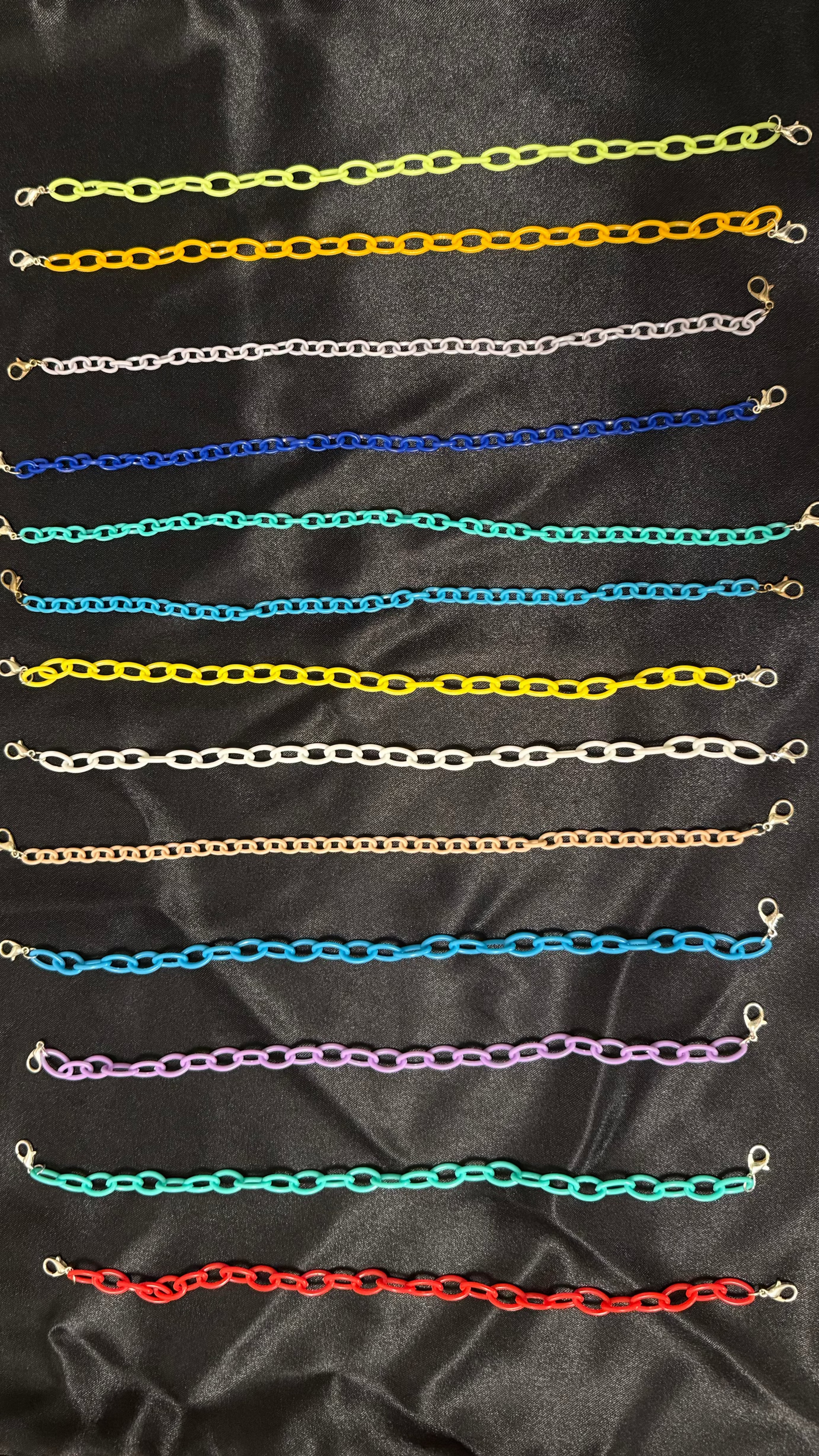 Collection of colorful chain necklaces on a black satin background