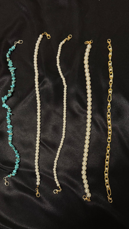 Four necklaces with different designs on a black fabric background