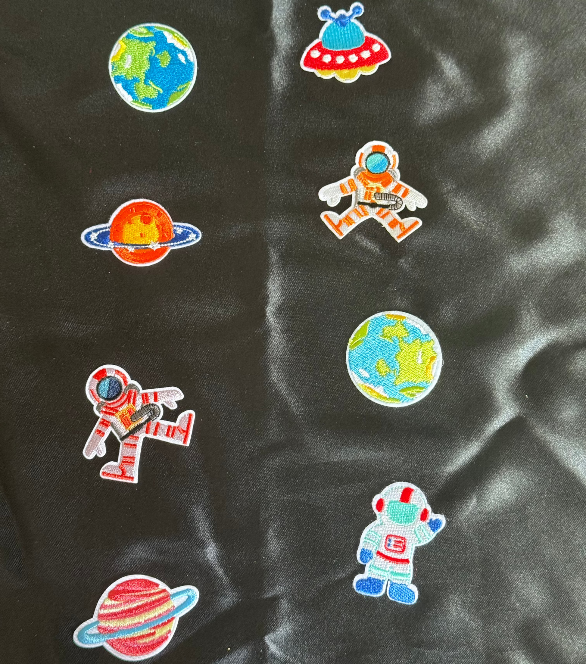 Colorful space-themed patches on a black fabric background