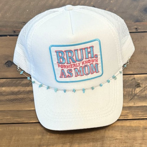 White cap with colorful patch that says "Bruh Formerly Known As Mom" in blue and red. Placed on a wooden surface