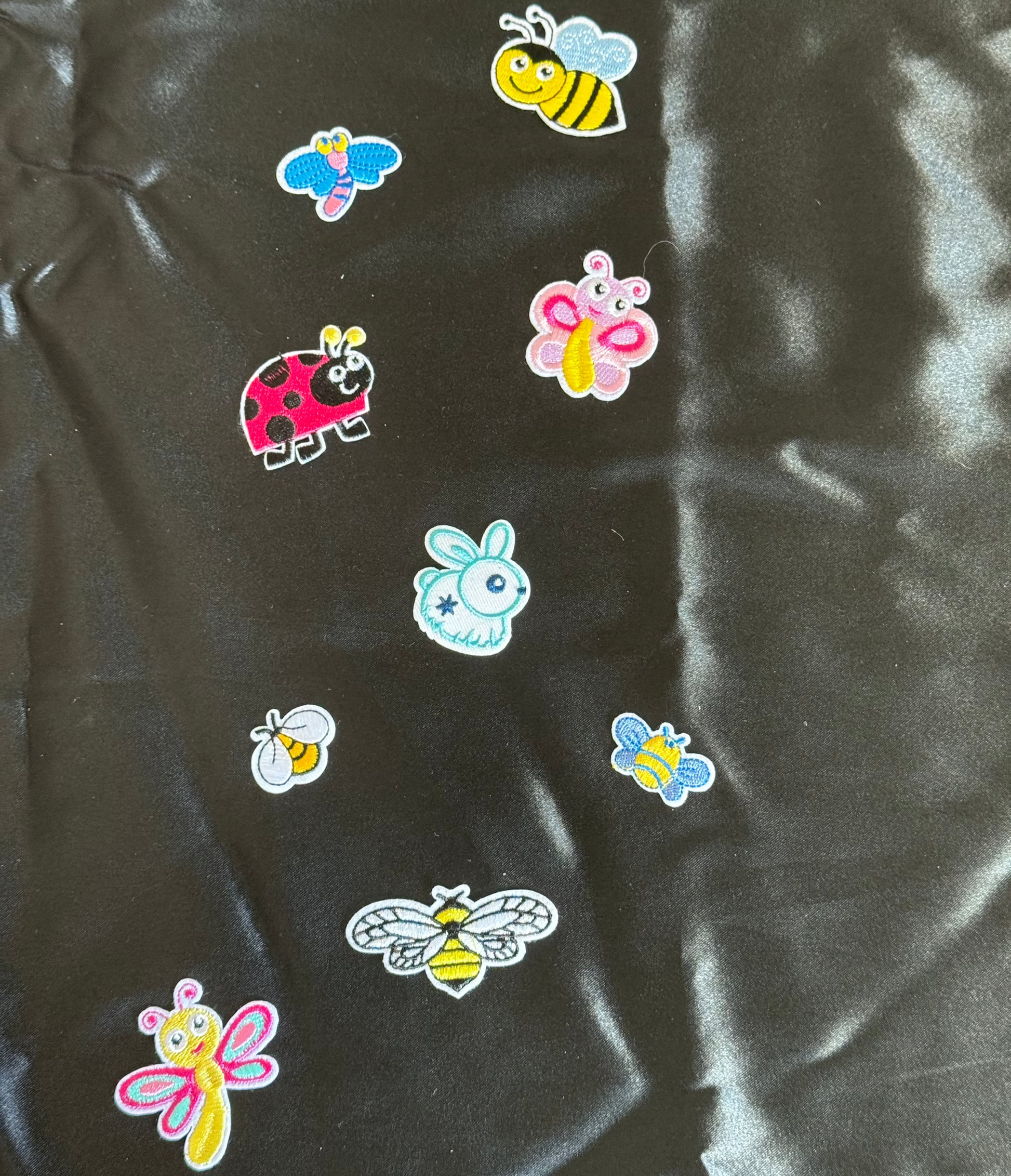 Colorful insect patches on a black satin surface