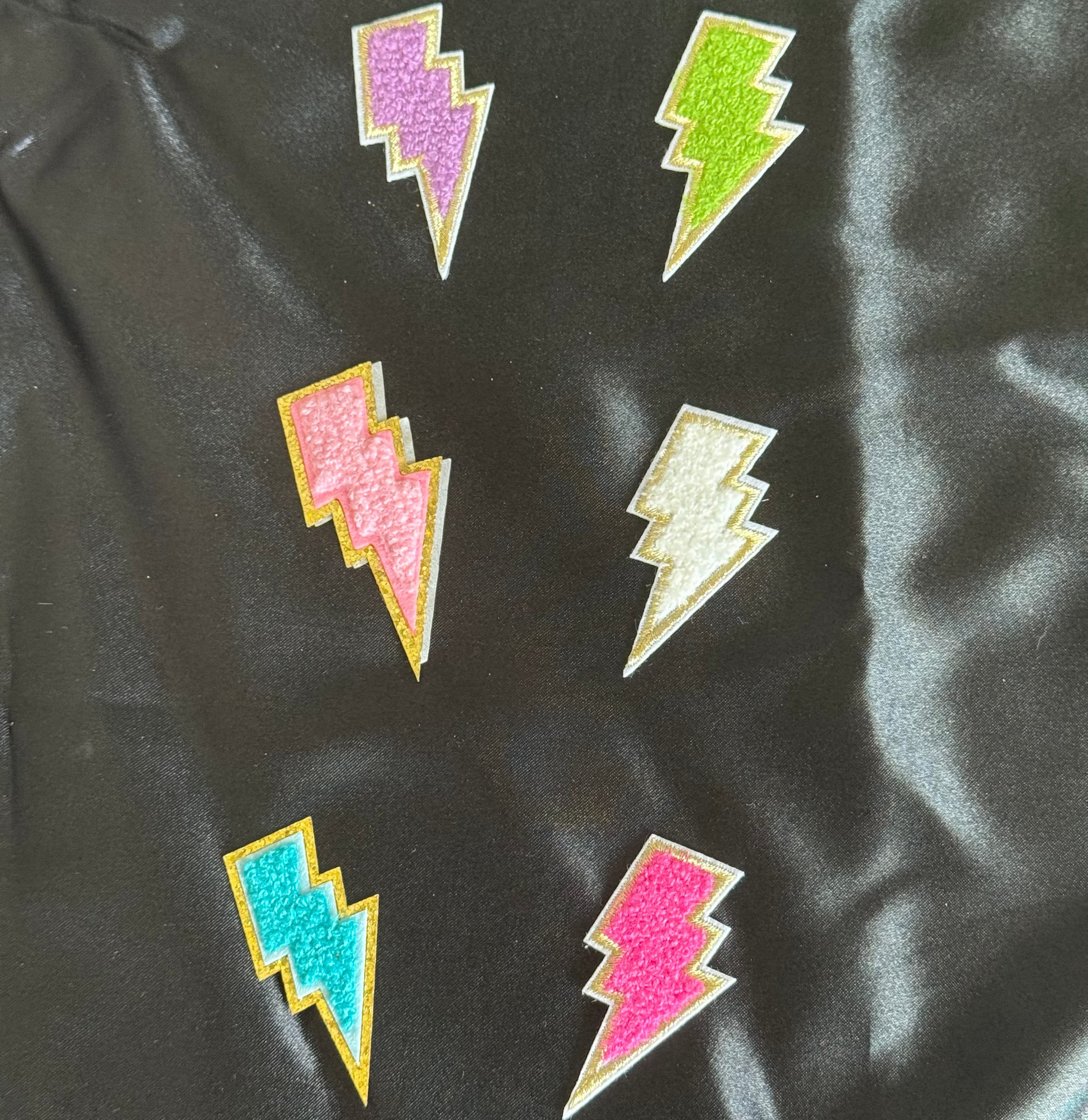 Colorful lightning bolt patches on a black fabric background