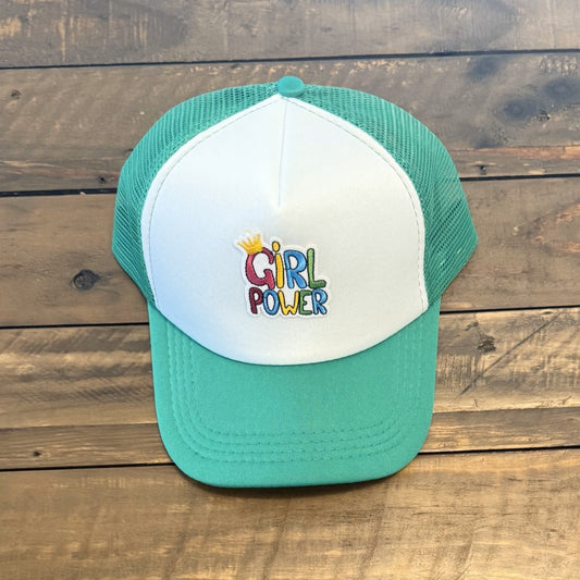 Green and white cap with colorful patch that says "Girl Power" placed on a wooden surface