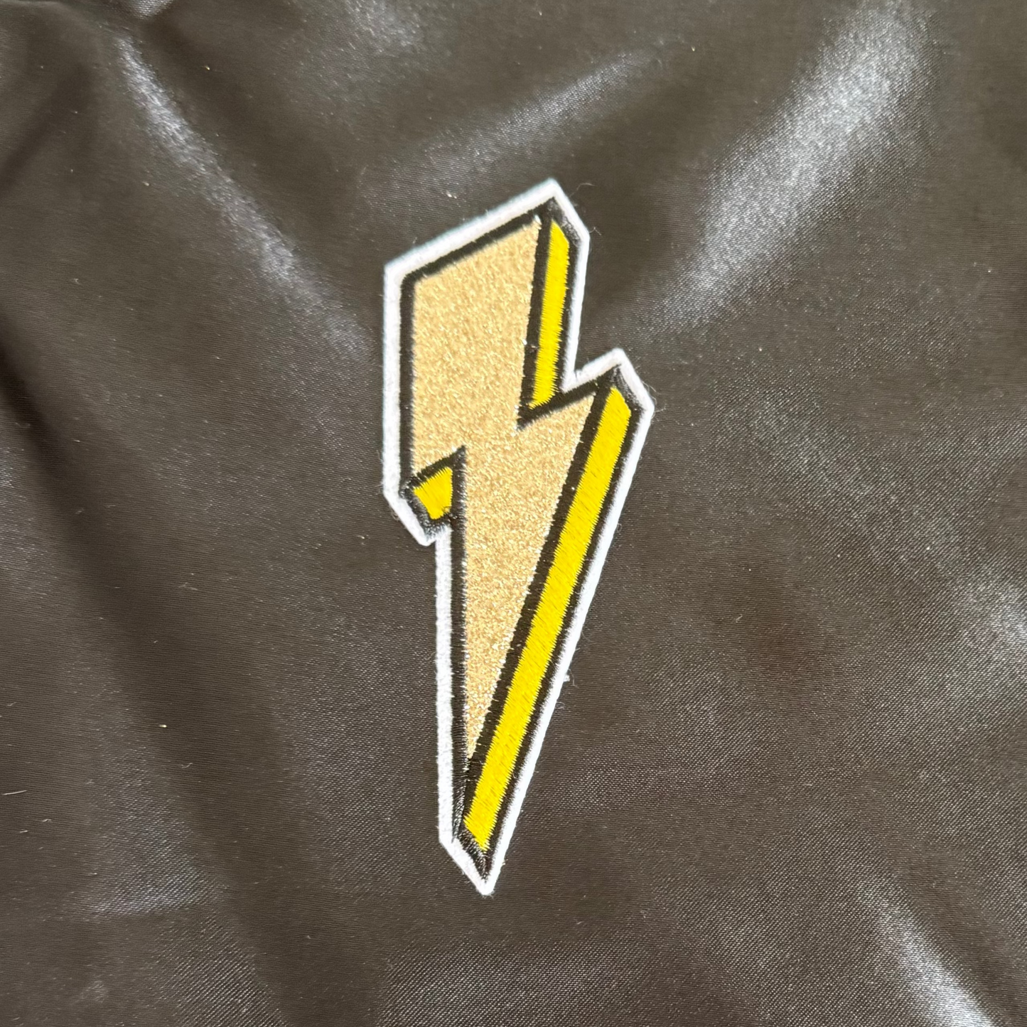 Yellow lightning bolt patch on a black fabric background