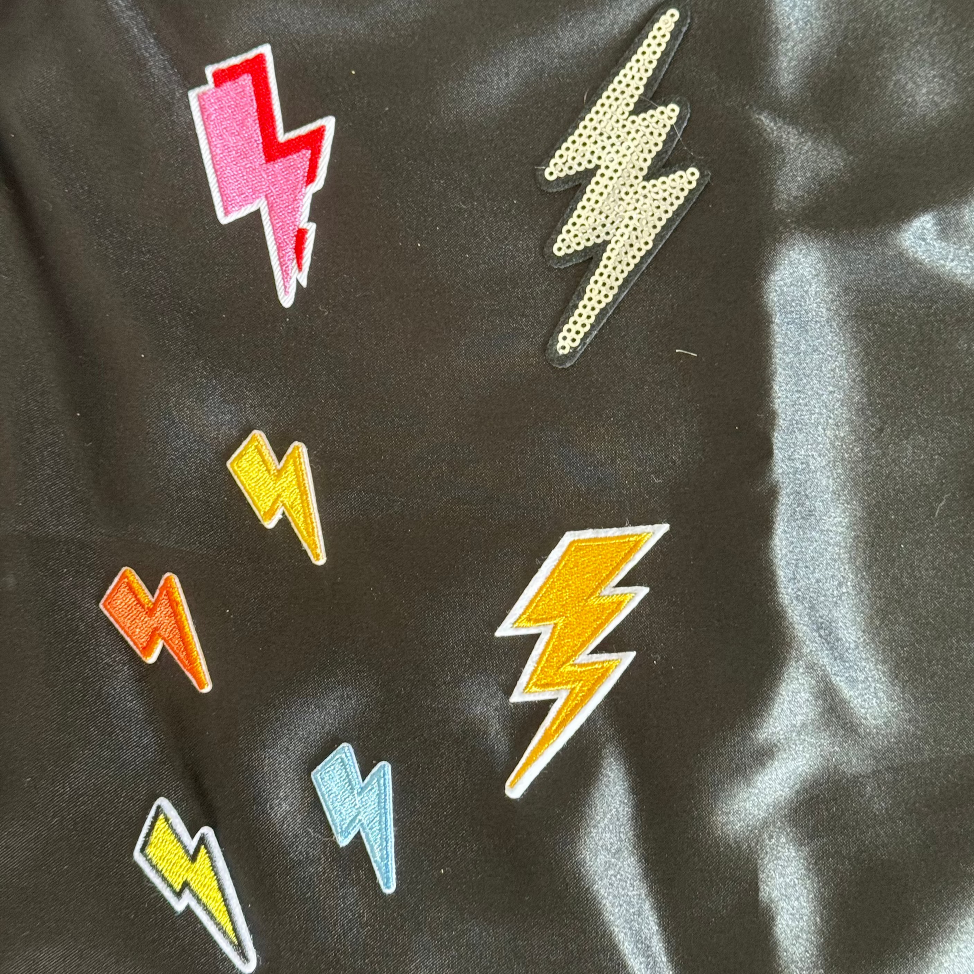 Colorful lightning bolt patches on a black fabric background